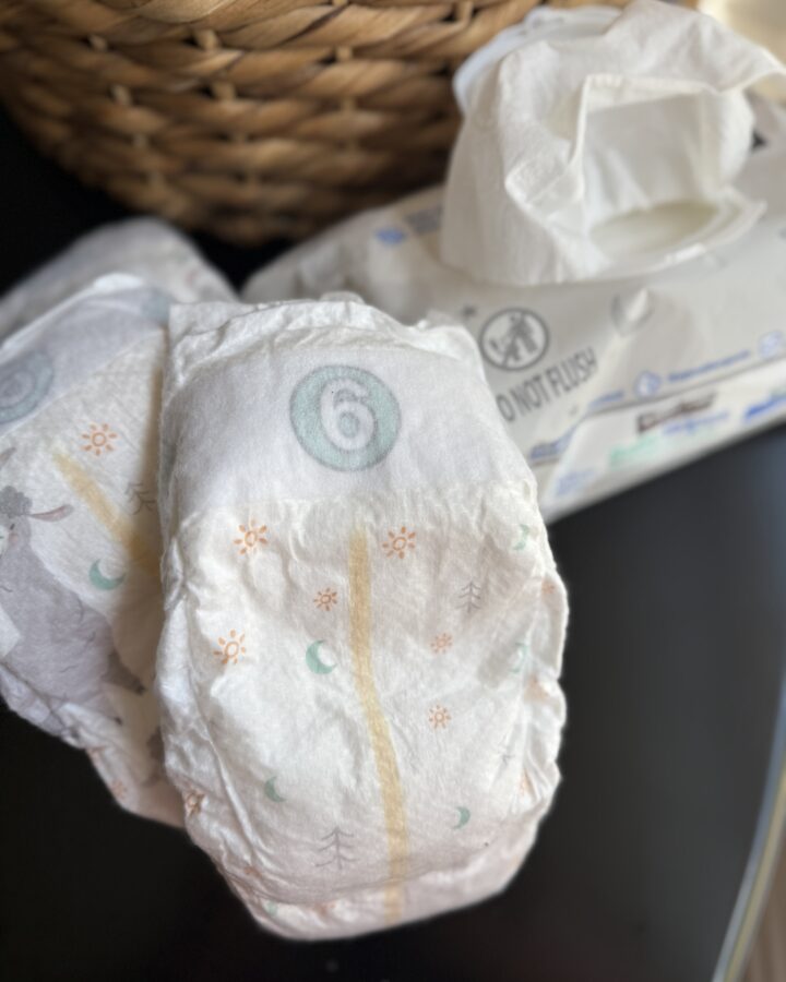 diapers and baby wipes on a table with basket in the background