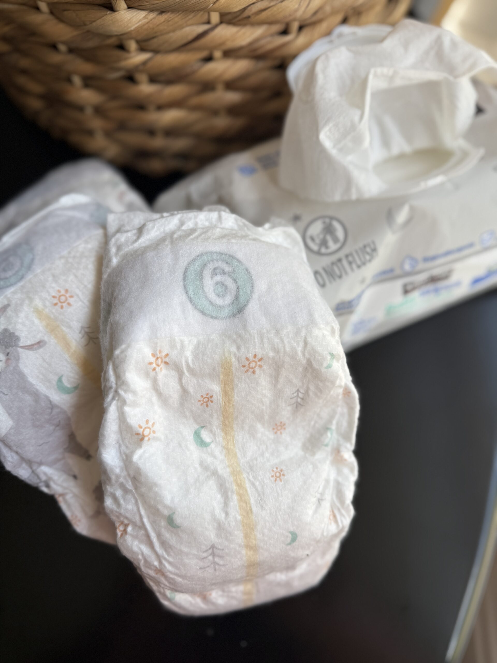 diapers and baby wipes on a table with basket in the background