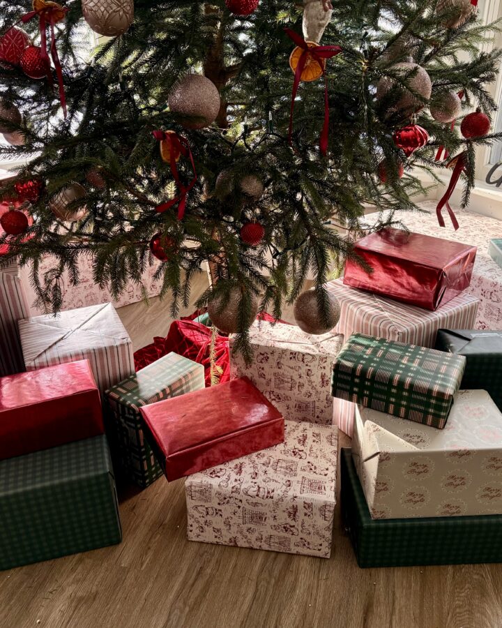 Bottom half of a decorated Christmas tree surrounded by wrapped gifts.