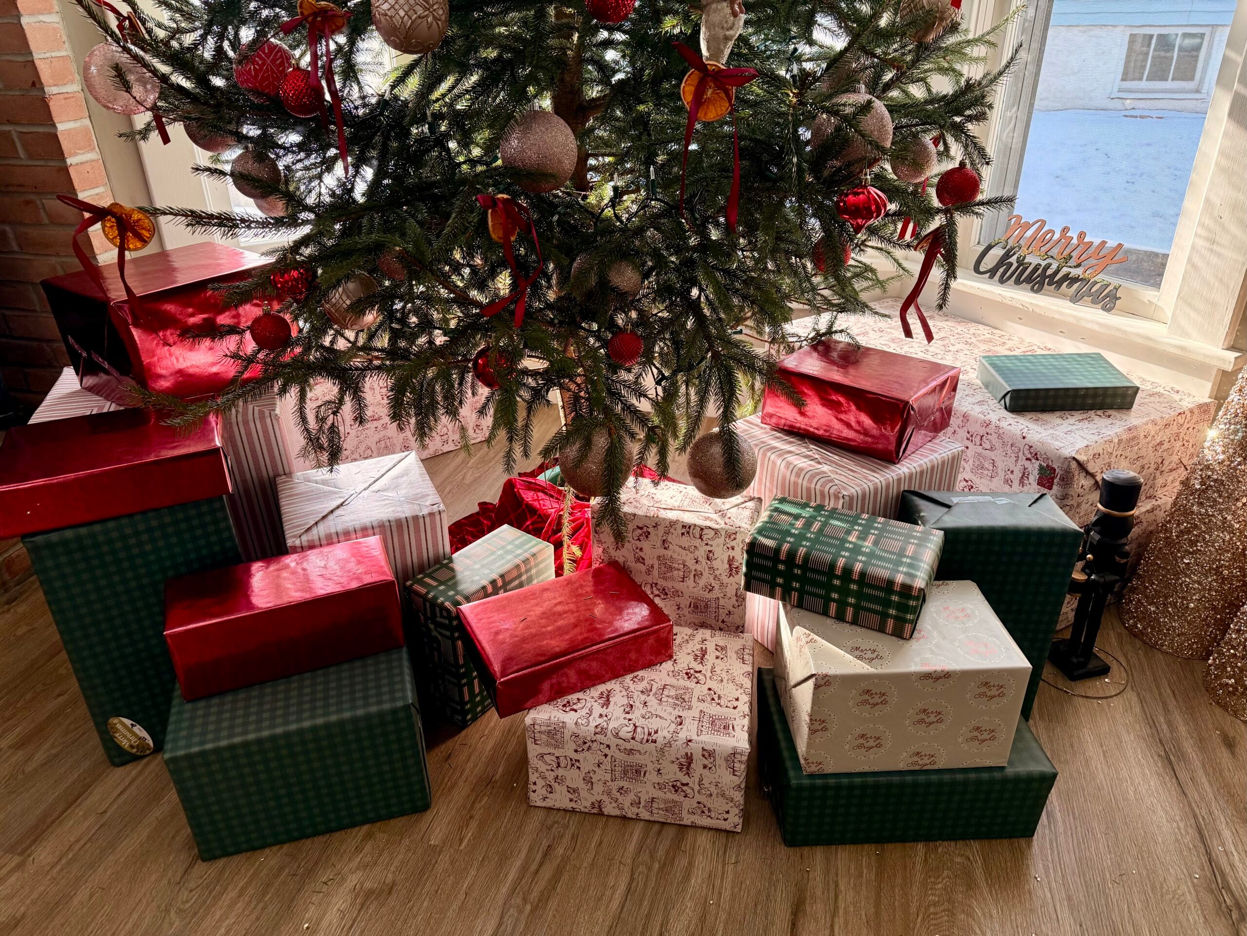 Bottom half of a decorated Christmas tree surrounded by wrapped gifts.
